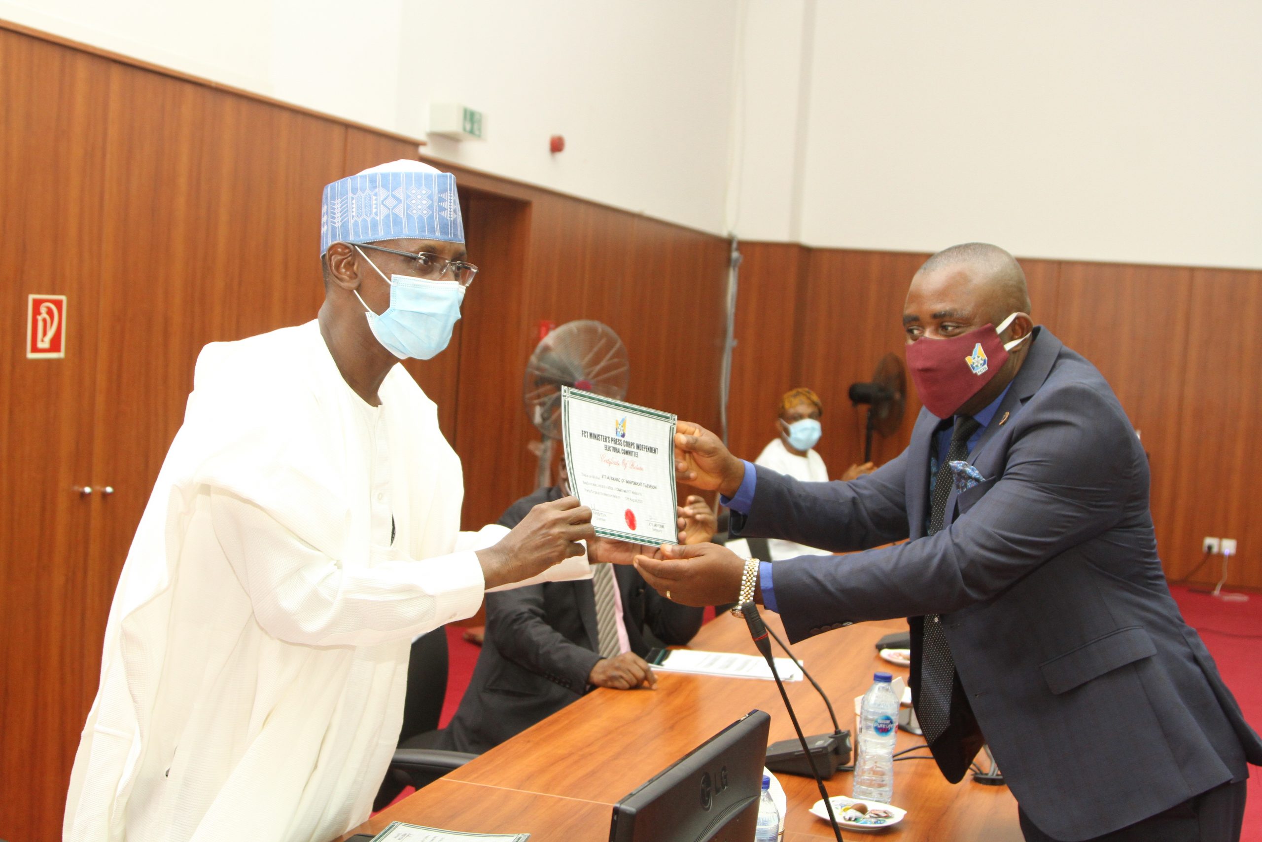 FCT Minister, Malam Muhammad Musa Bello presenting the Certificate of Return to Ikharo Attah, Chairman, FCT Minister's press Corps following the Swearing-in ceremony of the new EXCO yesterday in Abuja.